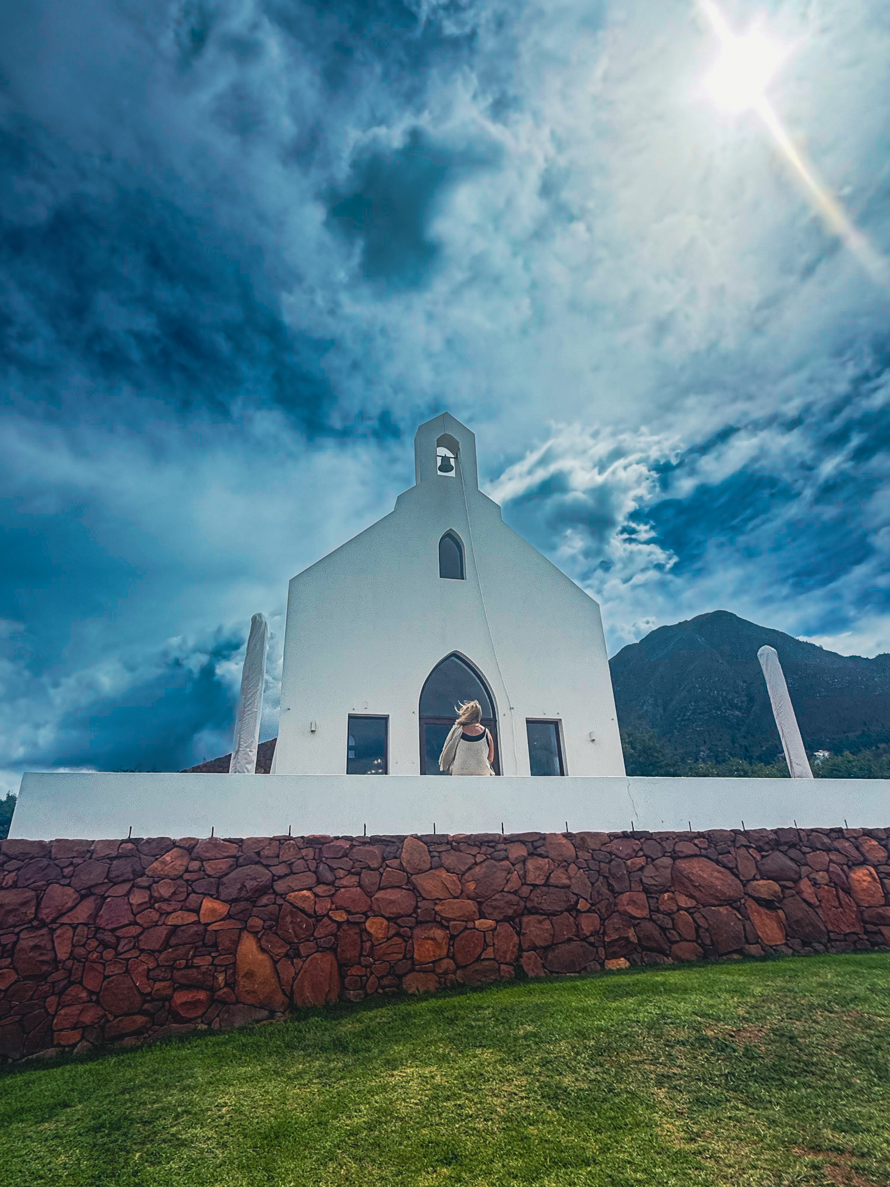 The distinctive whitewashed wine lounge of Ataraxia Wine Estate near Hermanus, with the Overberg mountains rising behind — one of the region's finest wine estates