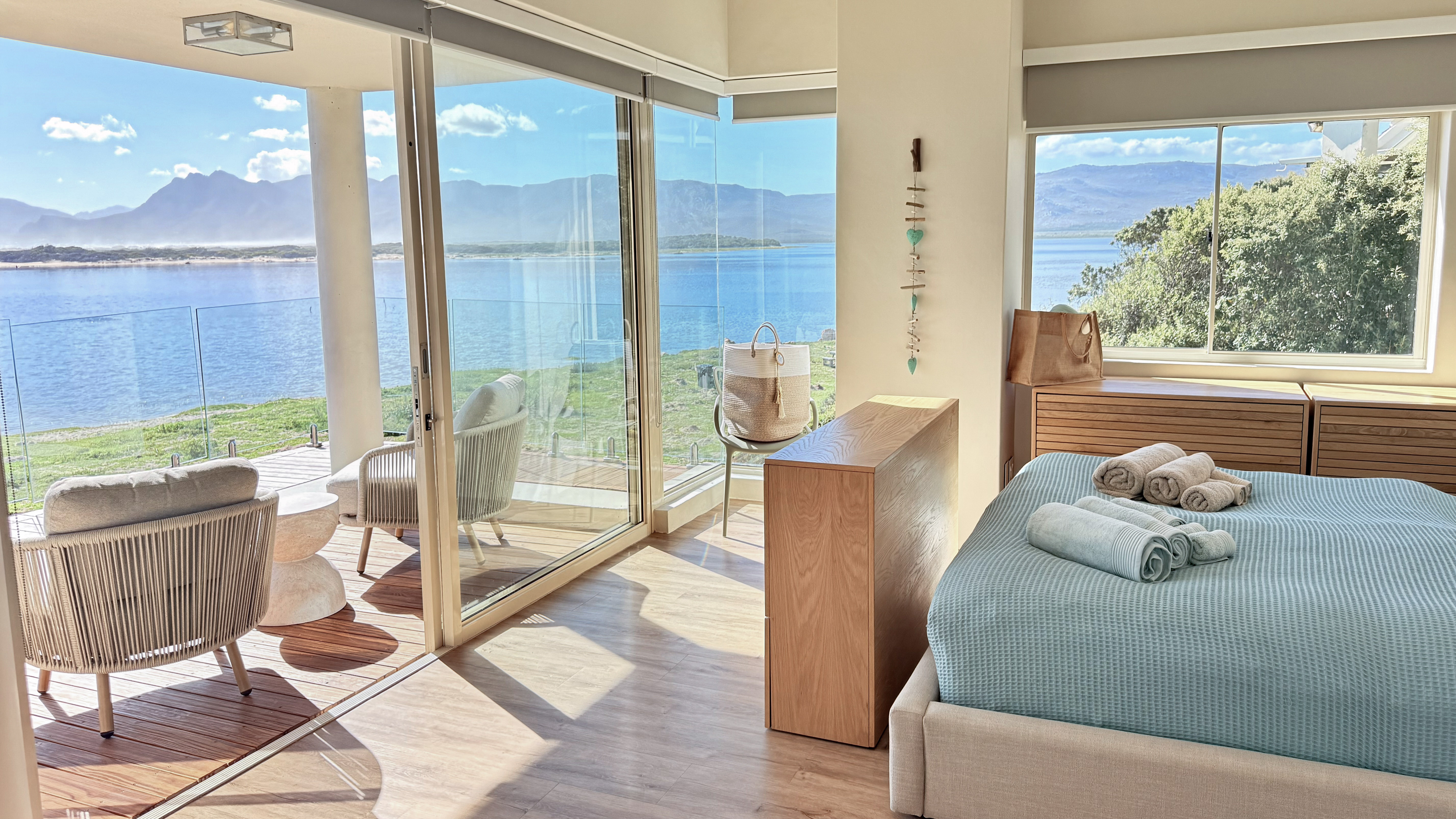 Master bedroom at MBIZI lagoon house with panoramic floor-to-ceiling lagoon and mountain views, Fisherhaven